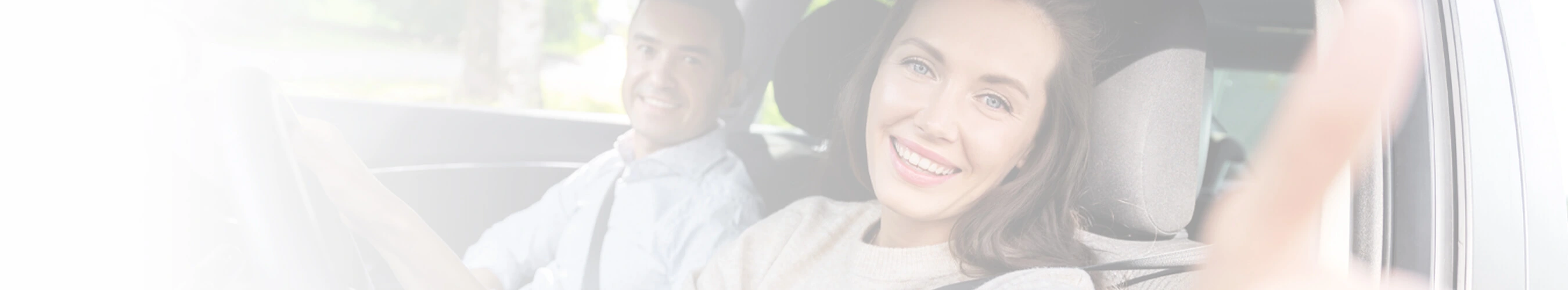 Smiling woman giving a thumbs-up from the passenger seat of a car with a man seated beside her