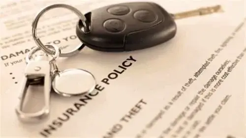 A set of car keys on top of an auto insurance policy document 