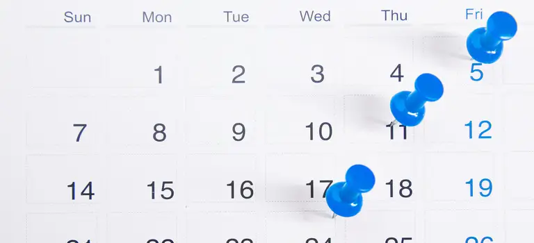 Calendar with blue pushpins marking specific dates, emphasizing an auto policy payment due date circled on the 30th