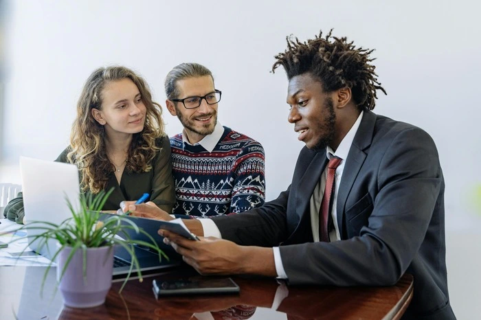 Insurance agent discussing policy options with two clients at an office desk