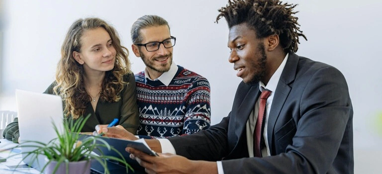 Insurance agent discussing policy options with two clients at an office desk