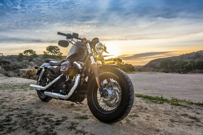 Black motorcycle parked on a scenic dirt path at sunset