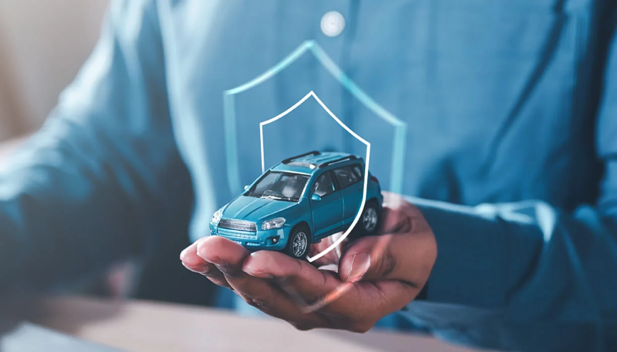 A person holding a small blue car model in their hands, overlaid with a digital shield icon, symbolizing protection and SR-22 insurance coverage